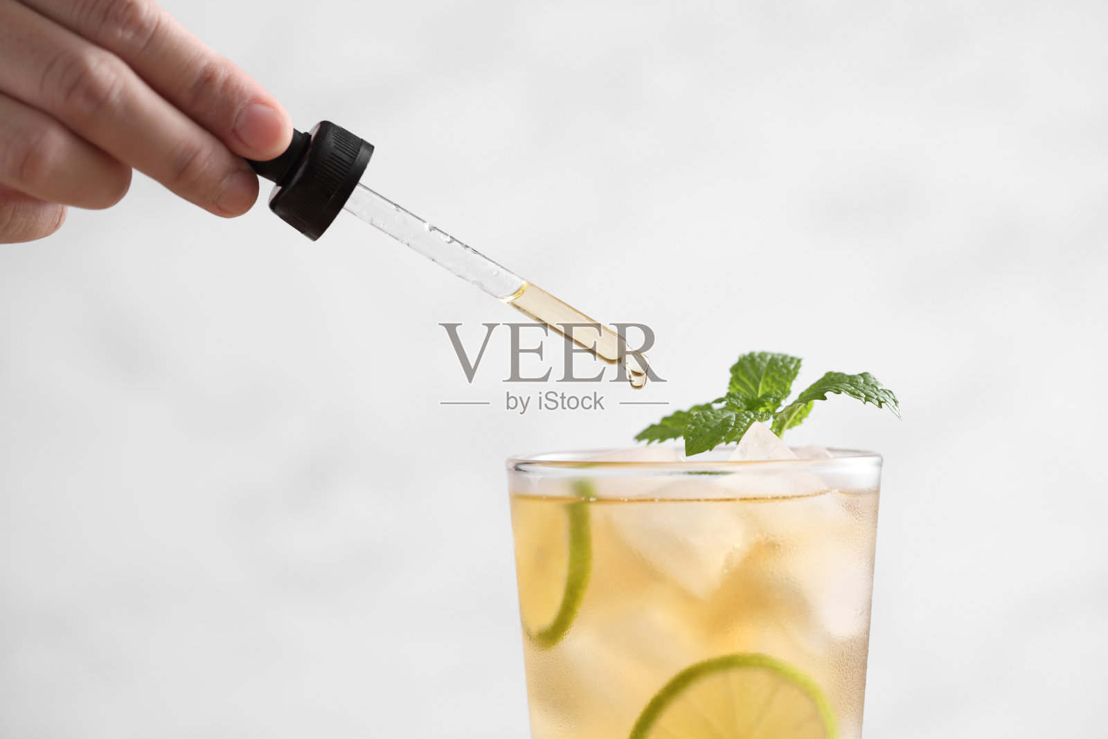 食品设计师用滴管在玻璃杯里用柠檬装饰冰茶照片摄影图片