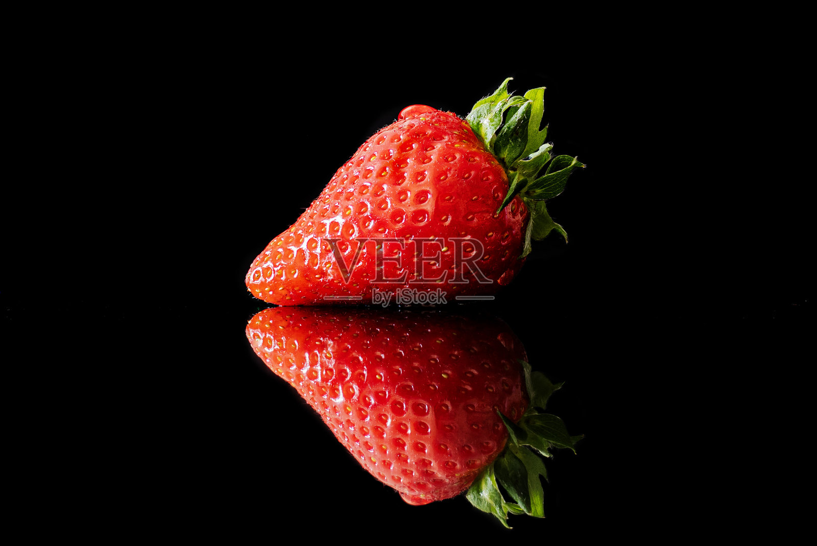 黑色倒影表面和黑色背景上的草莓照片摄影图片