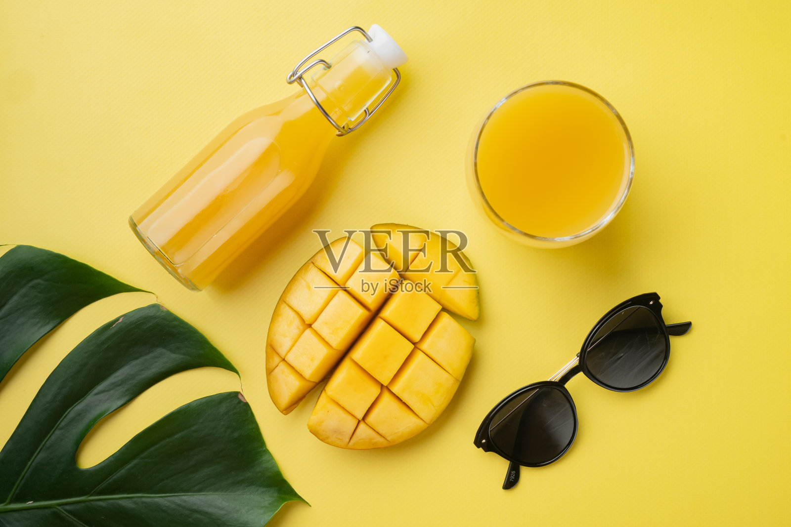 玻璃瓶的芒果汁，黄色纹理的夏季背景，俯视图平坦lay照片摄影图片