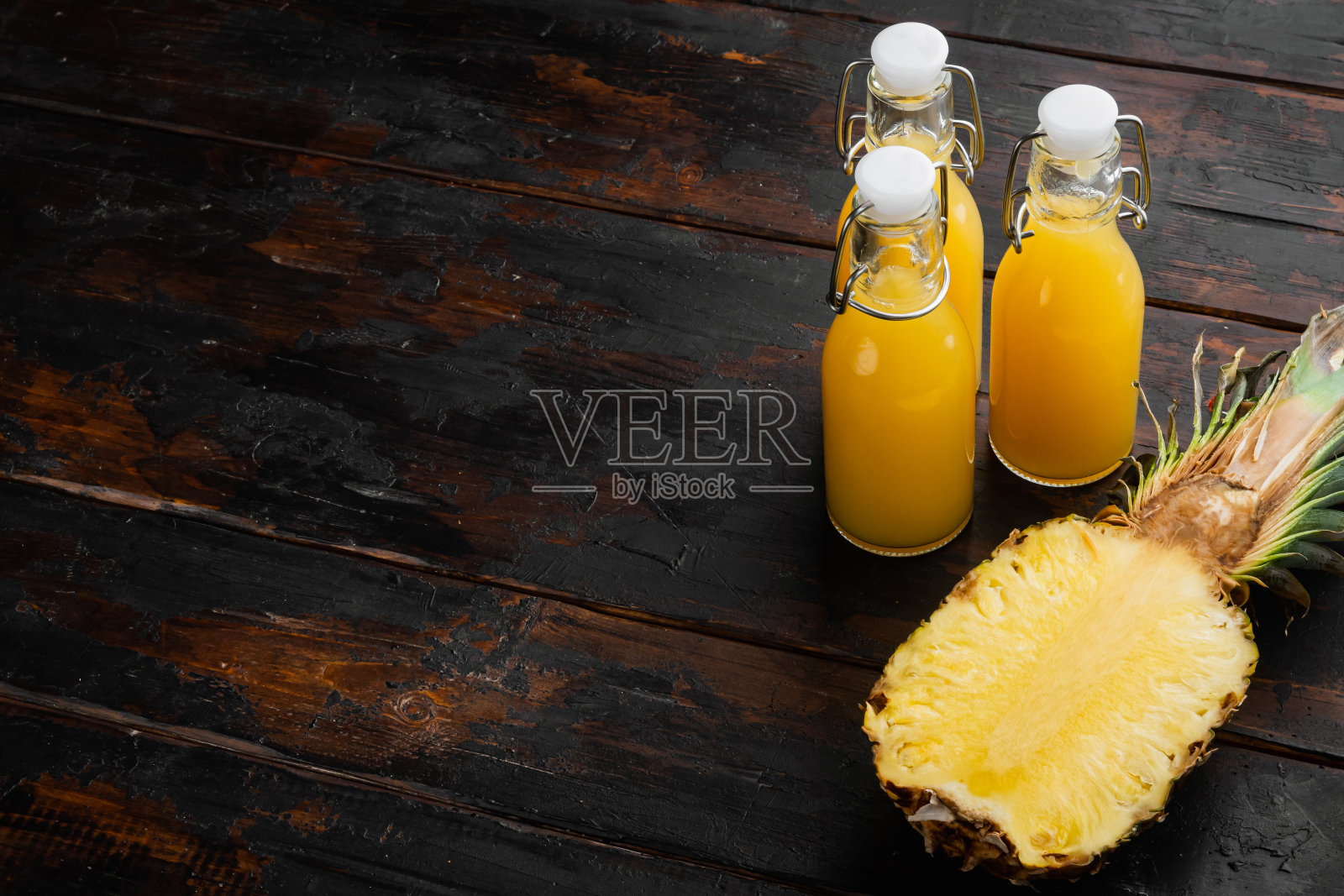 玻璃杯里的菠萝鲜汁，旧的深色木桌为背景，有文字拷贝空间照片摄影图片