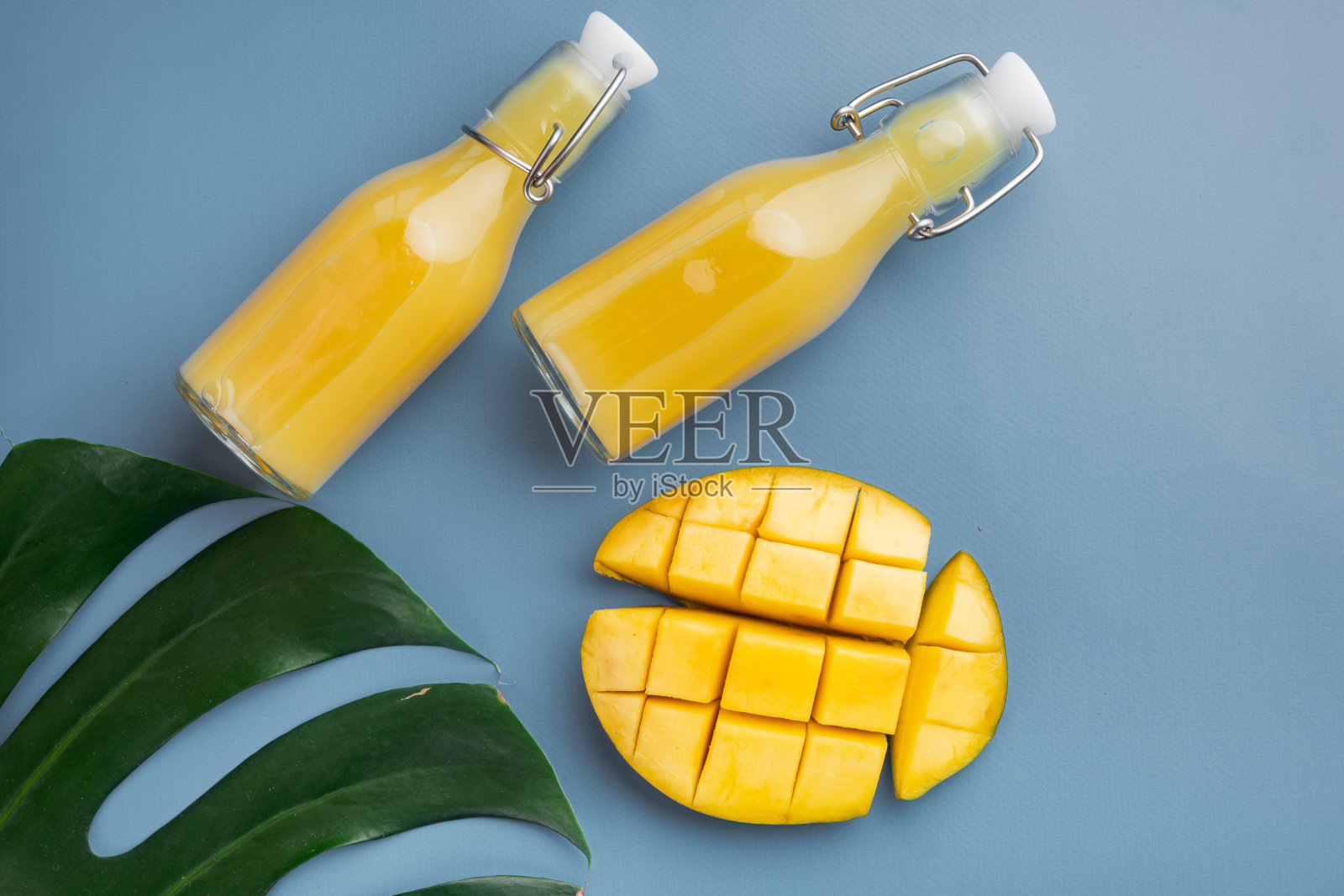 玻璃瓶的芒果汁，蓝色纹理的夏季背景，俯视图平坦lay照片摄影图片