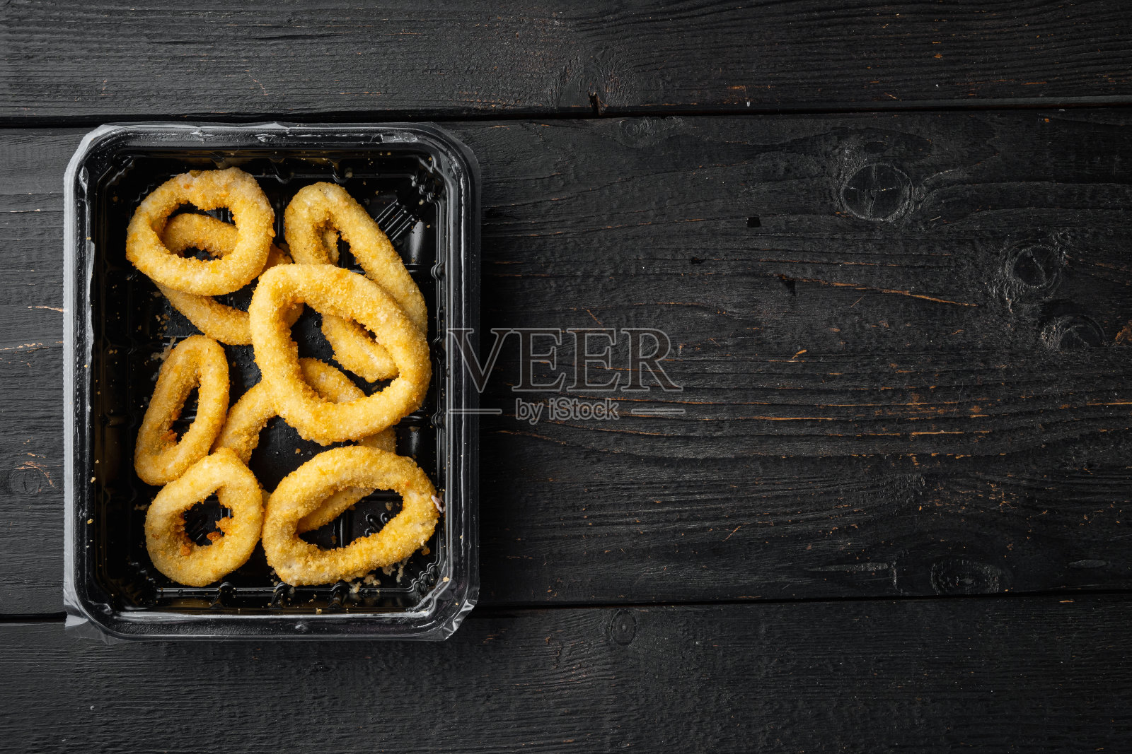 鱿鱼圈面包屑包，在黑色木桌背景，俯视图平铺，与文本复制空间照片摄影图片