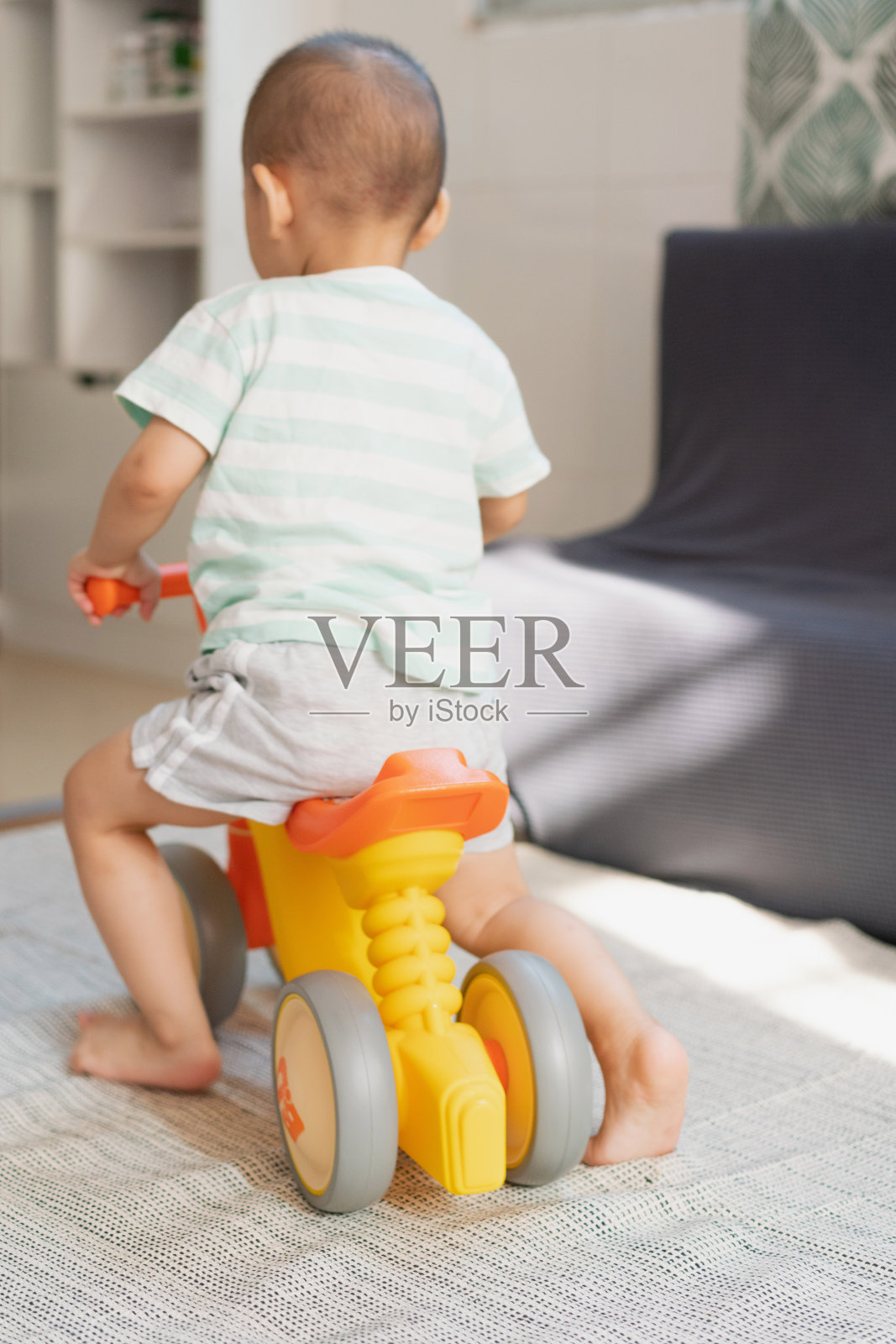 一个小男孩在房间里练习骑平衡自行车照片摄影图片