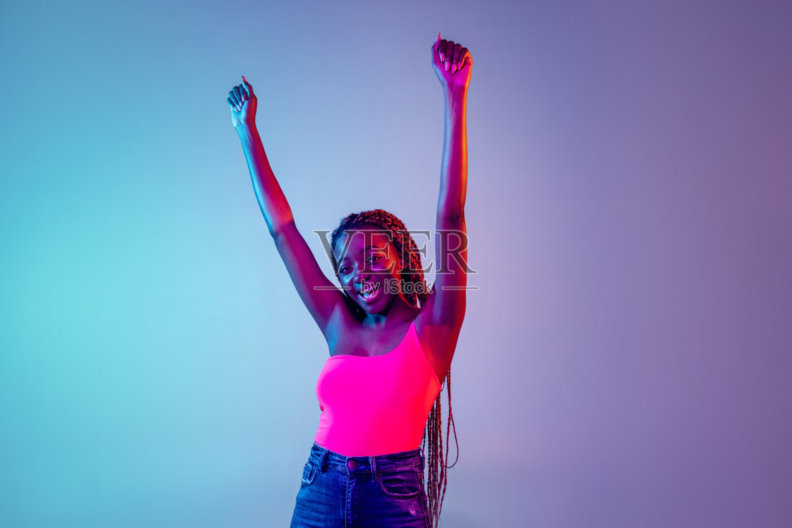 年轻的非洲妇女与非洲发式孤立在淡紫色霓虹灯背景。影棚拍摄。面部表情和人类情绪的概念照片摄影图片