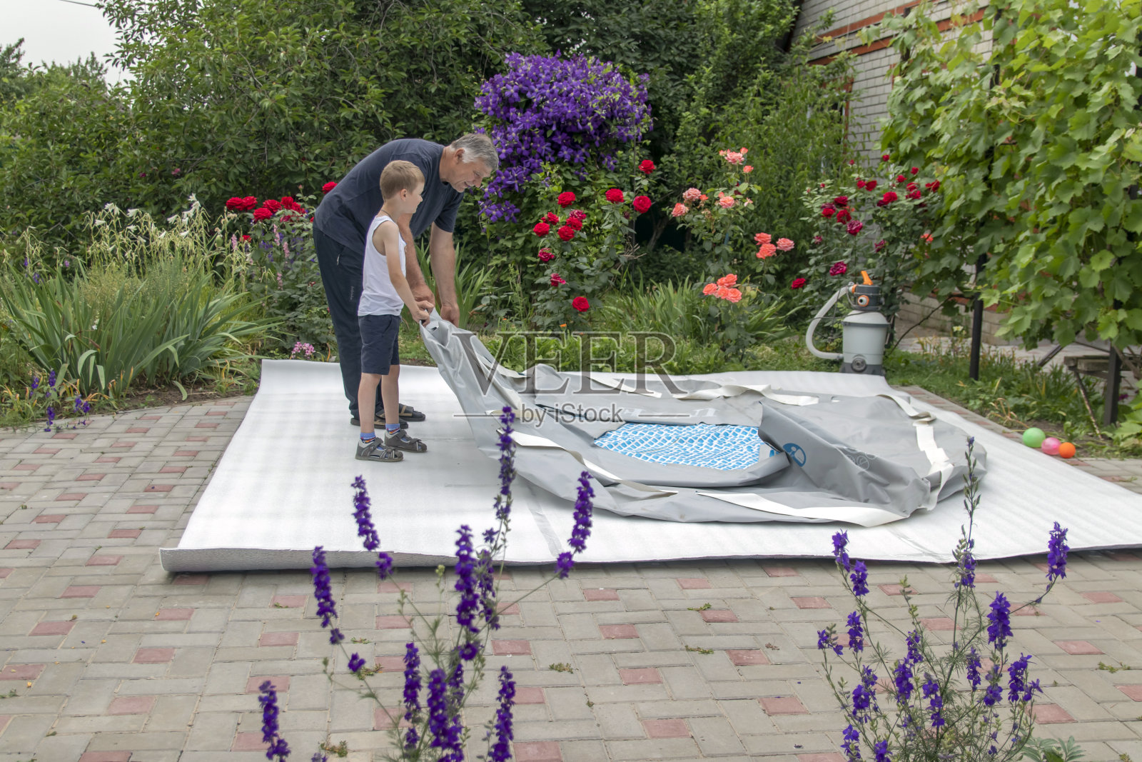 在温暖的夏日安装游泳池，男人和男孩正在组装框架游泳池照片摄影图片
