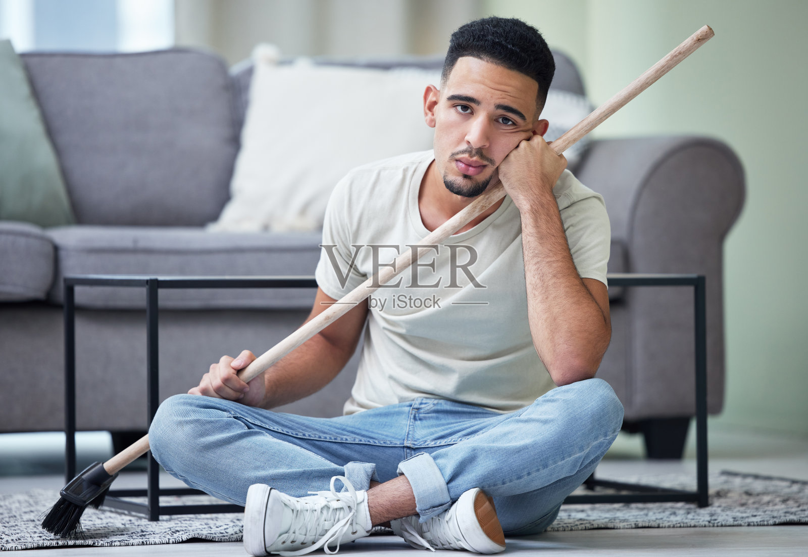 一个年轻人在家拿着扫帚照片摄影图片