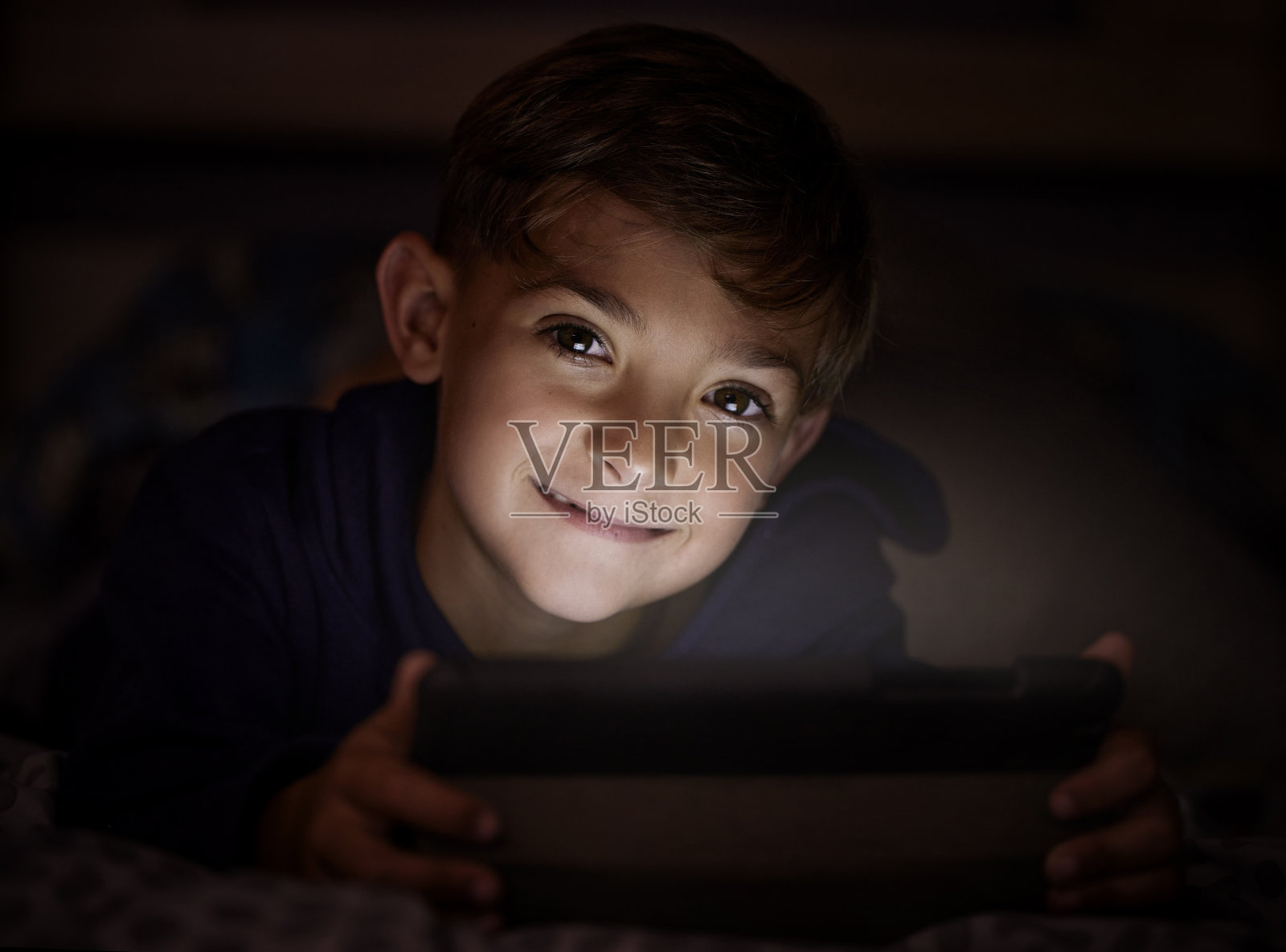 晚上使用平板电脑的可爱小男孩肖像照片摄影图片