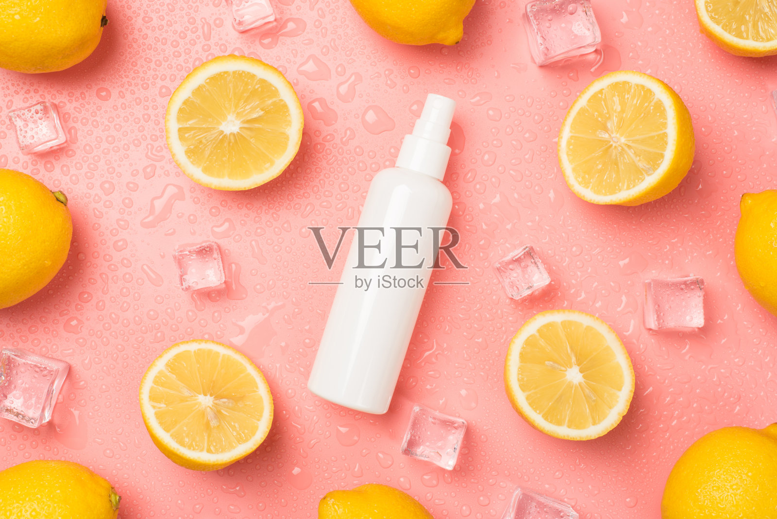 俯视图照片的白色喷雾瓶没有标签在中间的冰块水滴一半和整个黄色柠檬孤立的淡粉色背景与空白空间照片摄影图片