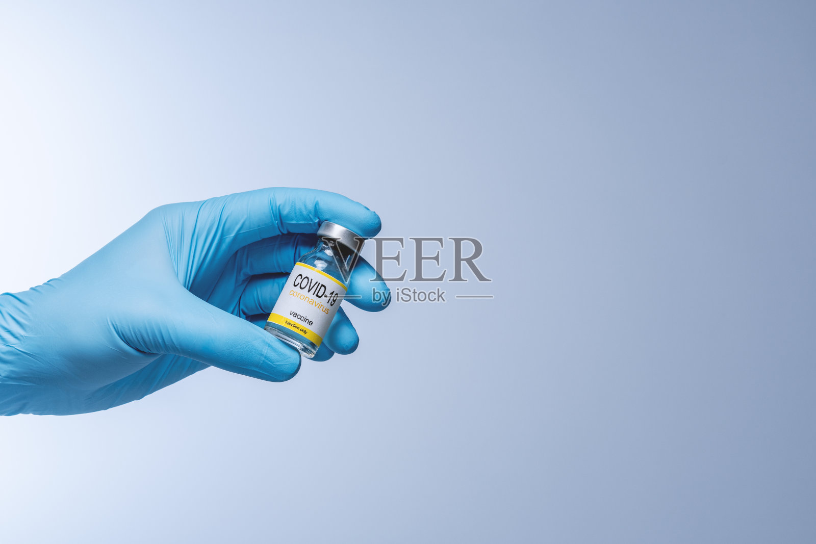 医生在蓝色乳胶手套拿着玻璃小瓶药。疫苗接种、免疫接种、治疗Covid - 19冠状病毒感染。医疗保健和医疗概念。照片摄影图片