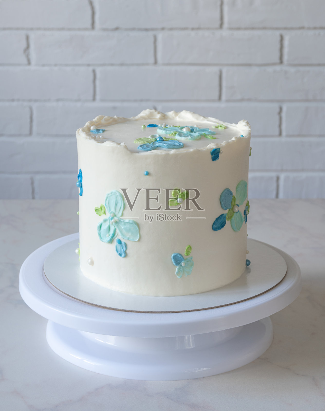 高高的白色蛋糕，点缀着奶油色的蓝色花朵照片摄影图片