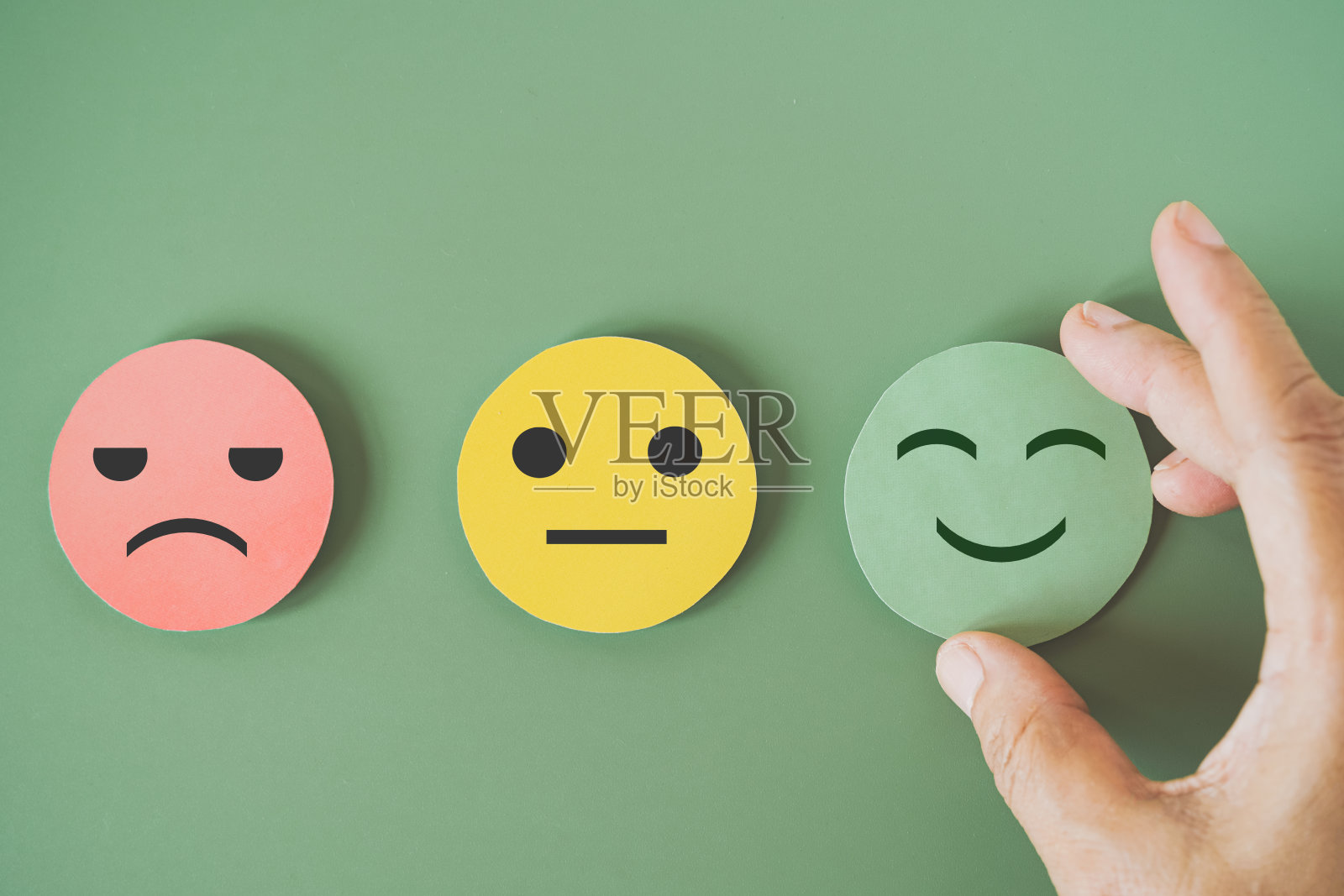 手选绿色剪纸，快乐笑脸上绿色背景进行心理健康评估，积极思考，世界心理卫生日，客户点评，体验，满意度调查理念照片摄影图片