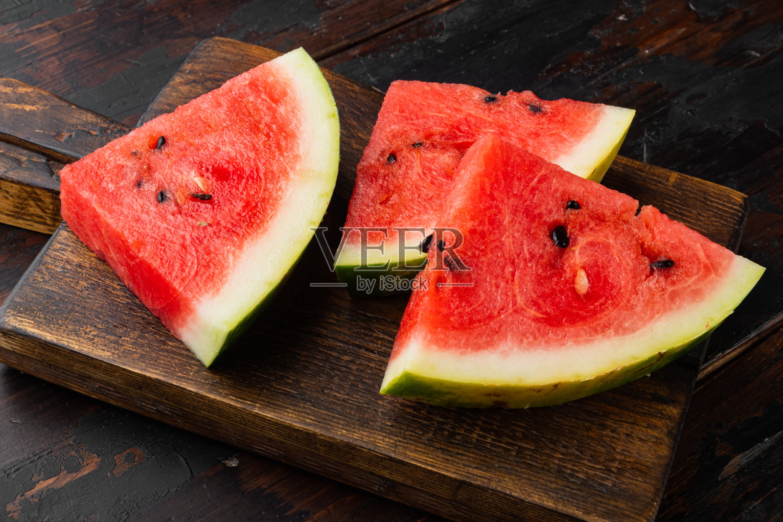 西瓜切，在旧的深色木桌的背景上照片摄影图片