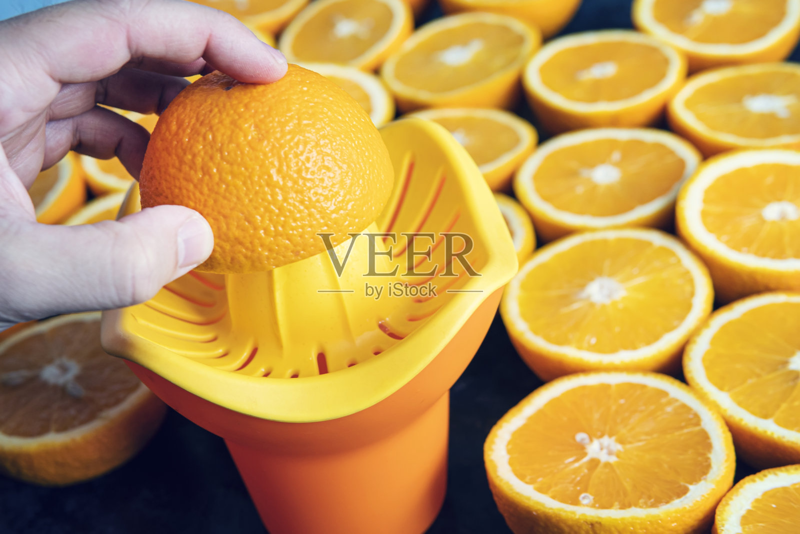 近距离观察用手从柑橘类水果中榨汁的过程。健康食品,背景。橙色照片摄影图片
