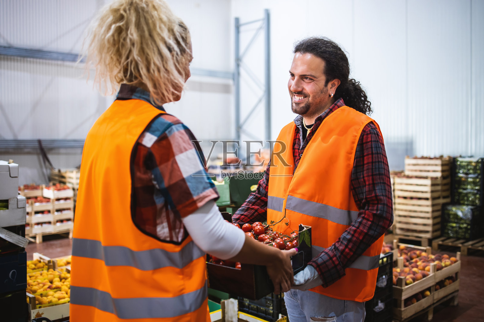 两个人一个年轻的男人和一个女孩，在一个水果蔬菜仓库工作。照片摄影图片