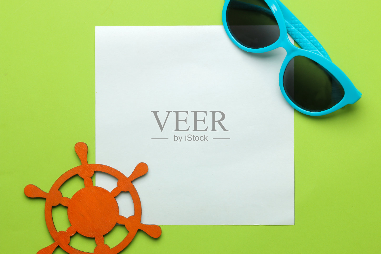 夏天的框架。在明亮的绿色背景上为你的文字、太阳镜和装饰航海方向盘提供纸框。俯视图照片摄影图片