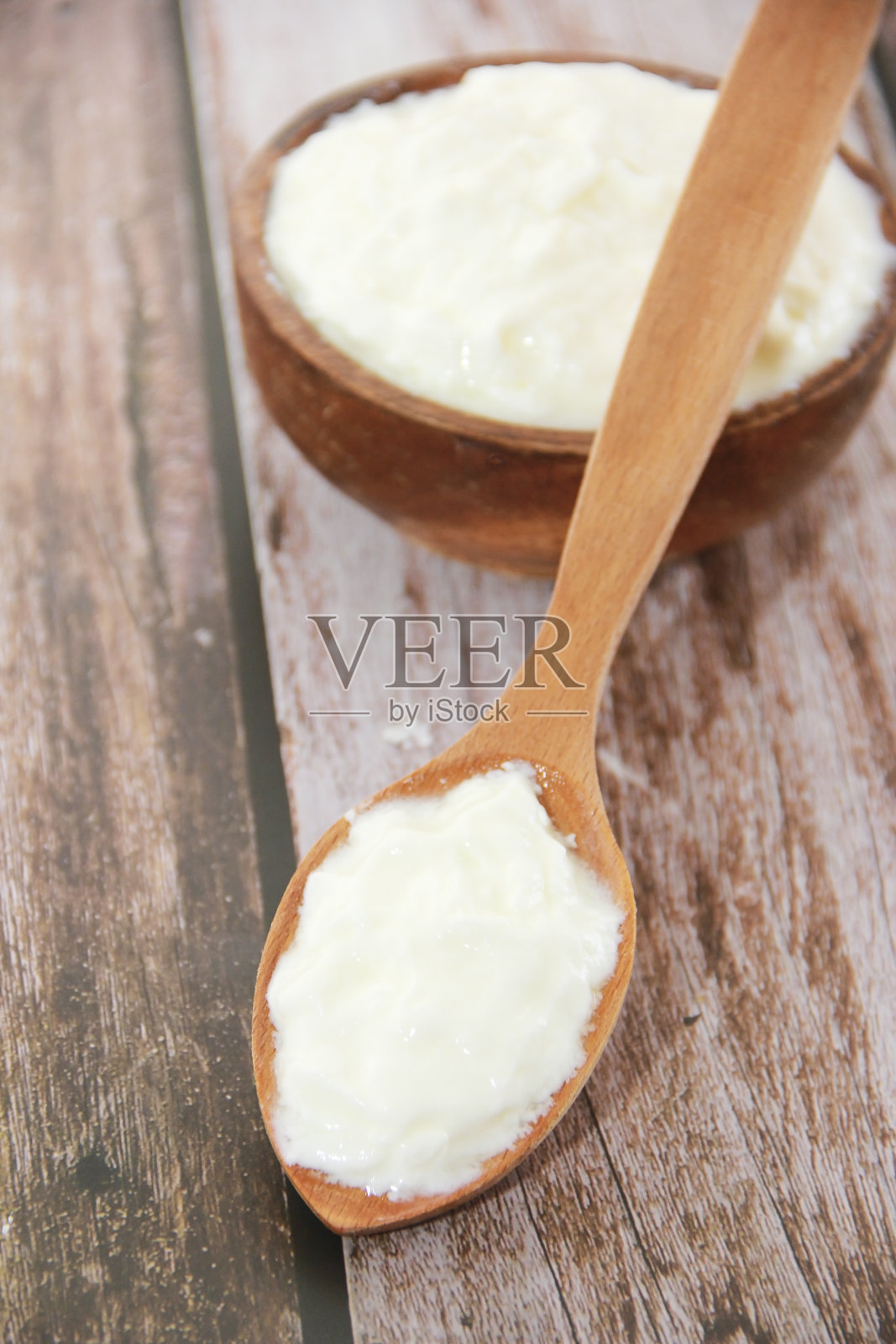 用木勺和木盘盛着白牛奶酸奶照片摄影图片