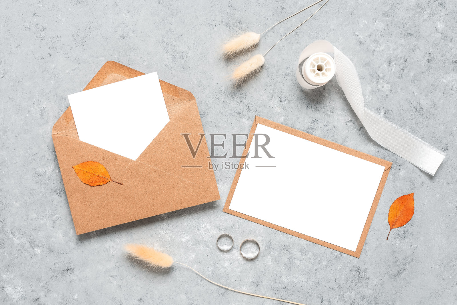 婚礼女性邀请卡模板。空白贺卡模型，棕色信封，结婚银戒指，干草lagurus和丝绸缎带。灰色的狼籍的背景。俯视图，平放。照片摄影图片