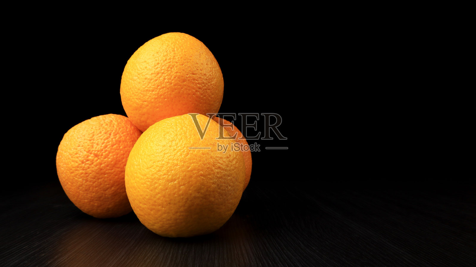 四个甜橙子堆在一个木质纹理上照片摄影图片