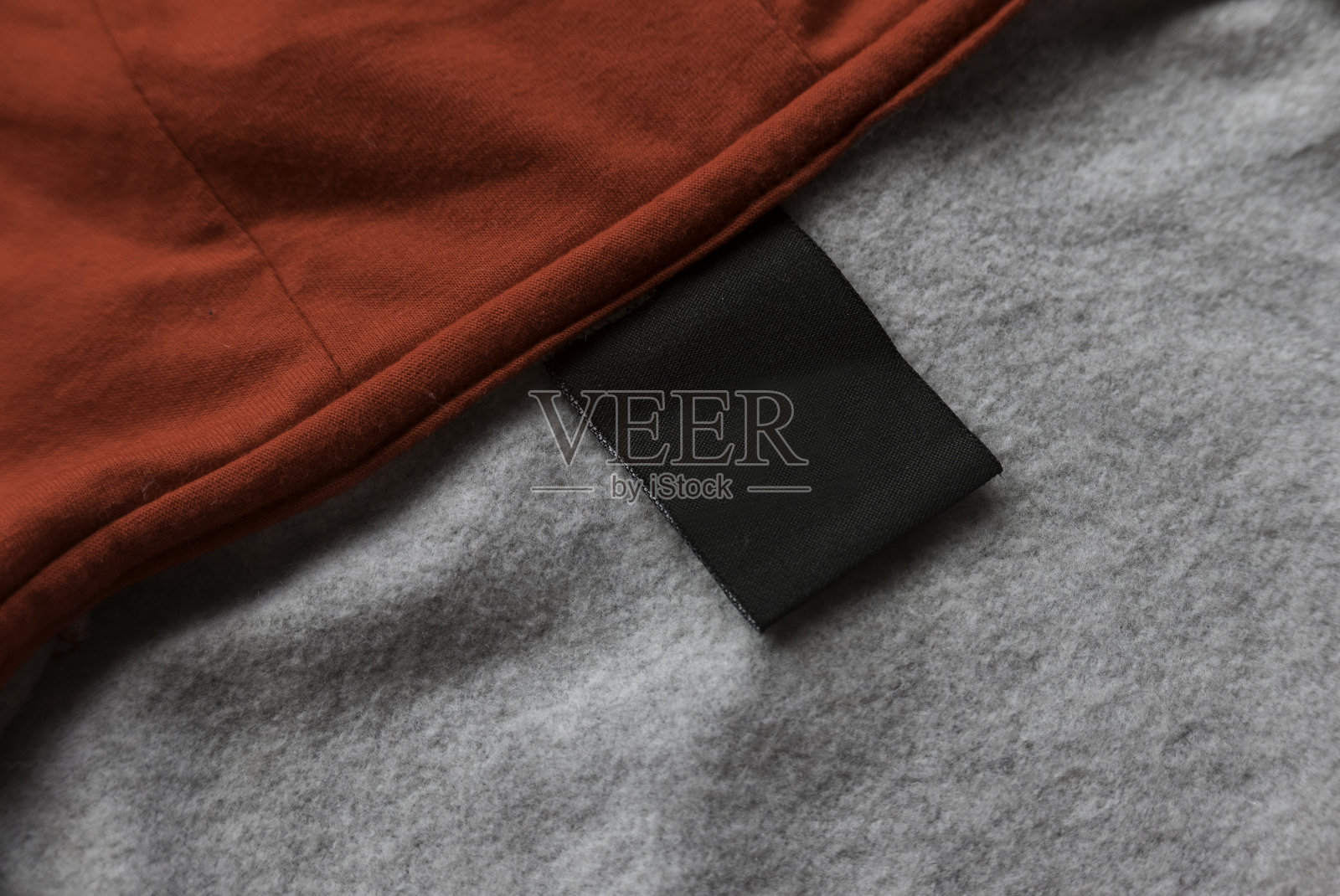 空白黑色洗衣护理衣服标签上的红色和灰色织物纹理背景。照片摄影图片