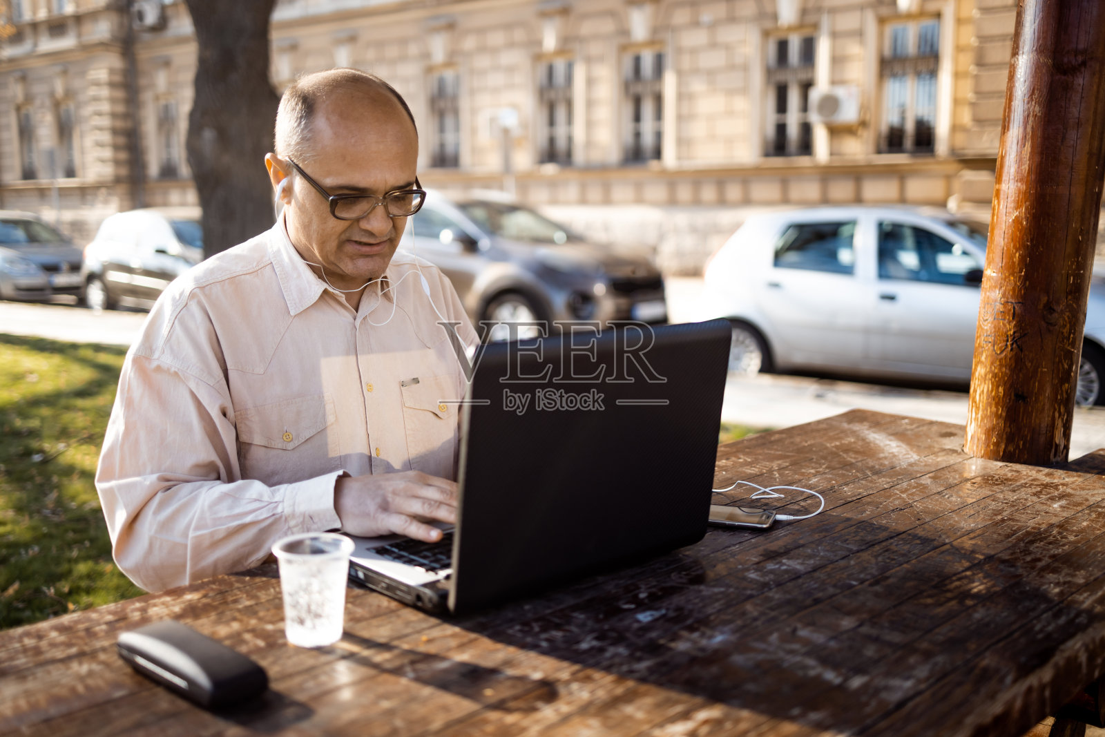 一个成熟的商人坐在公园的办公桌前用笔记本电脑工作照片摄影图片