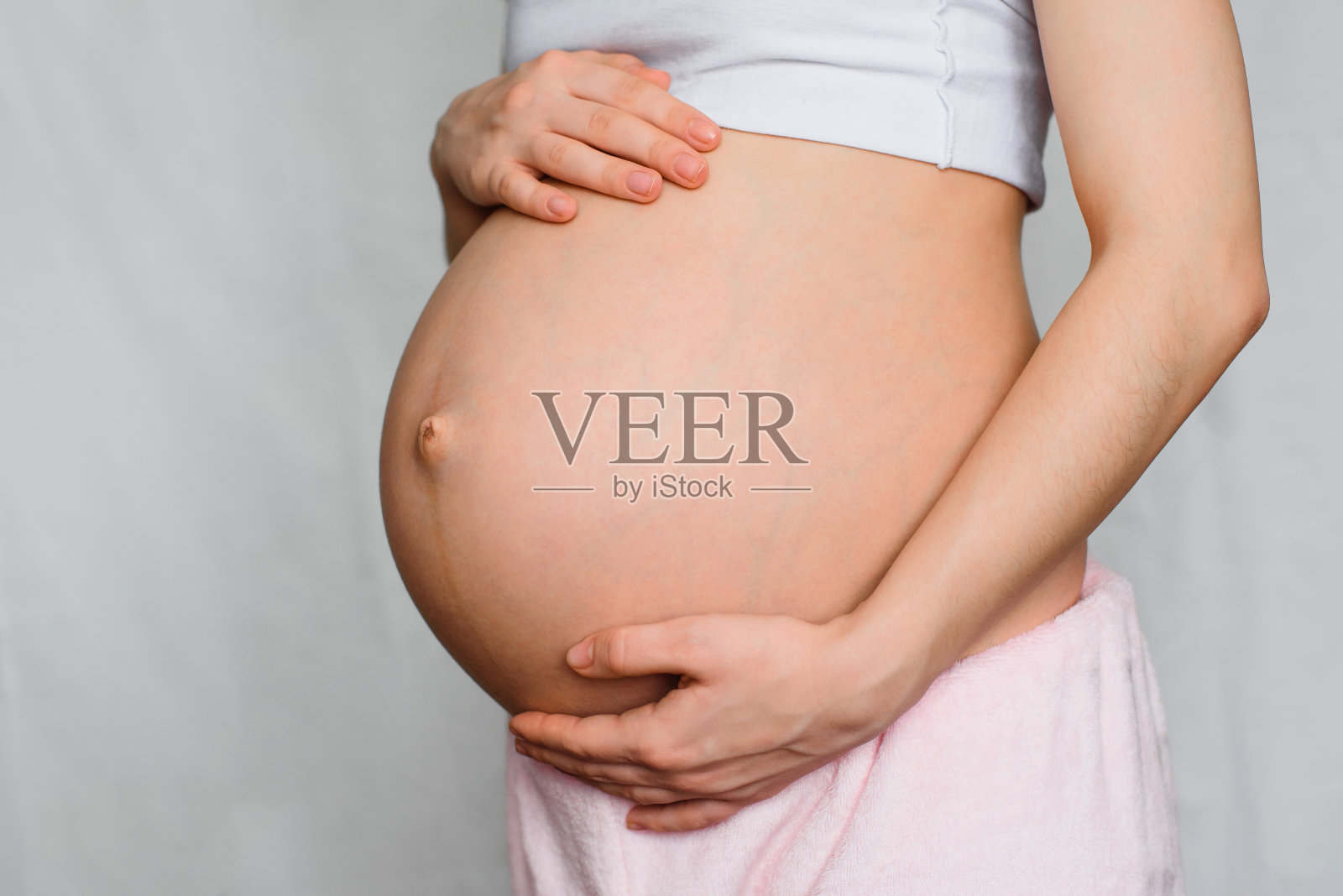 怀孕的女孩双手抱着你的肚子照片摄影图片