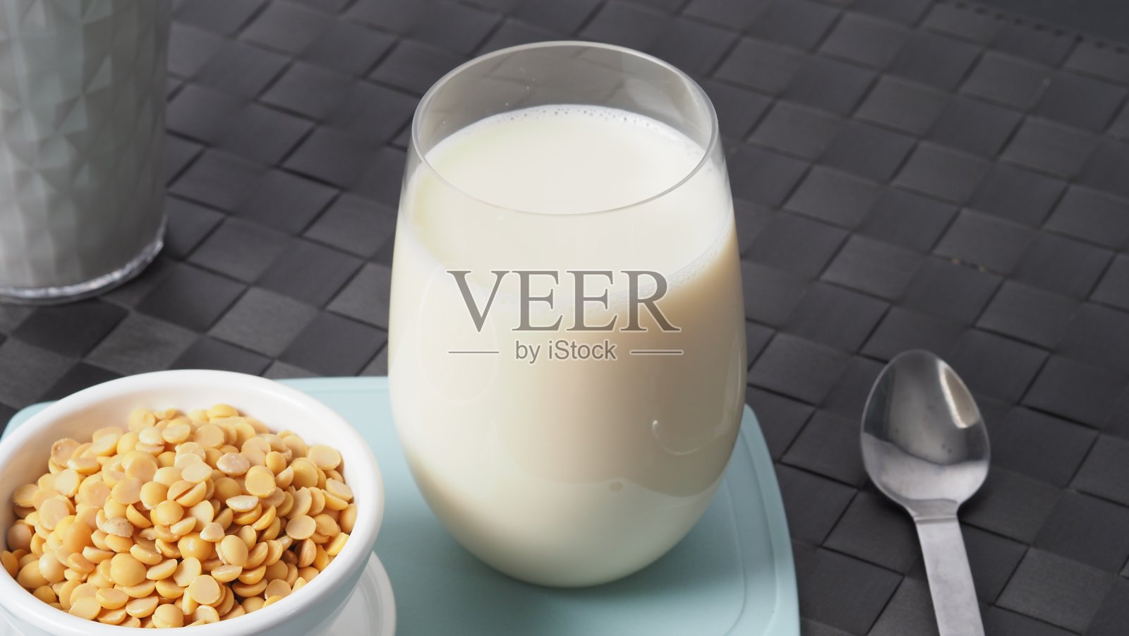 没有糖的豆奶添加在一个绿色塑料盘子垫上的玻璃。近距离图像自制健康豆奶饮料和大豆在小碗。在工作室拍摄的黑色背景。豆浆。照片摄影图片