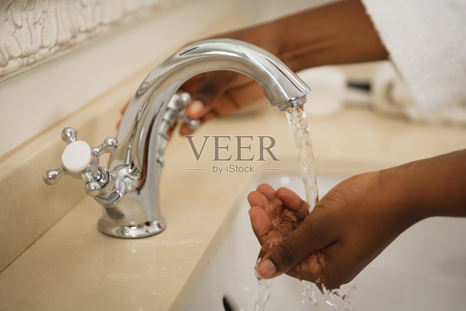 中部非洲裔美国妇女在浴室穿着浴衣在盆洗手照片摄影图片