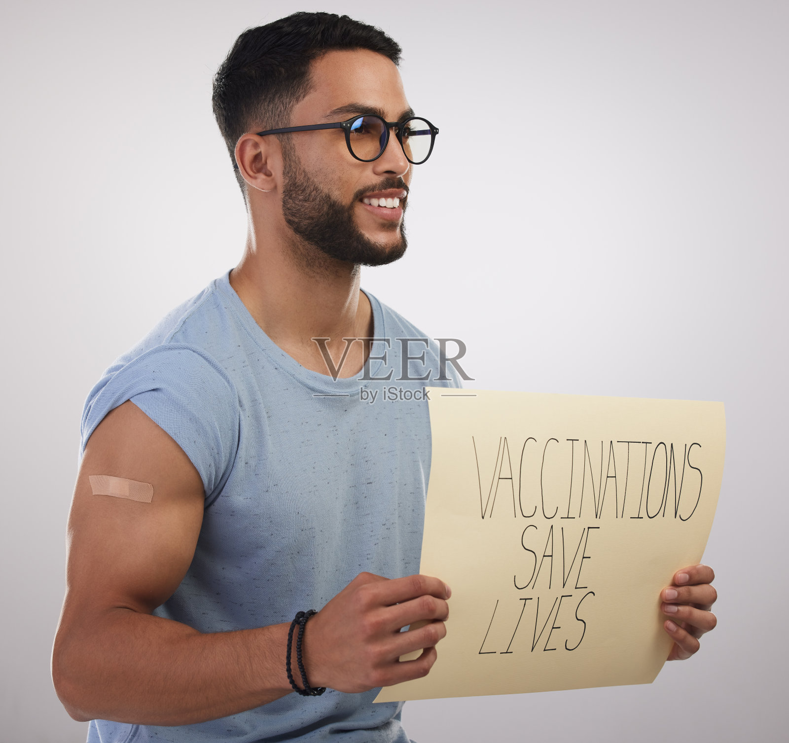 一个英俊的年轻人独自坐在演播室里，拿着一张接种疫苗后的海报照片摄影图片