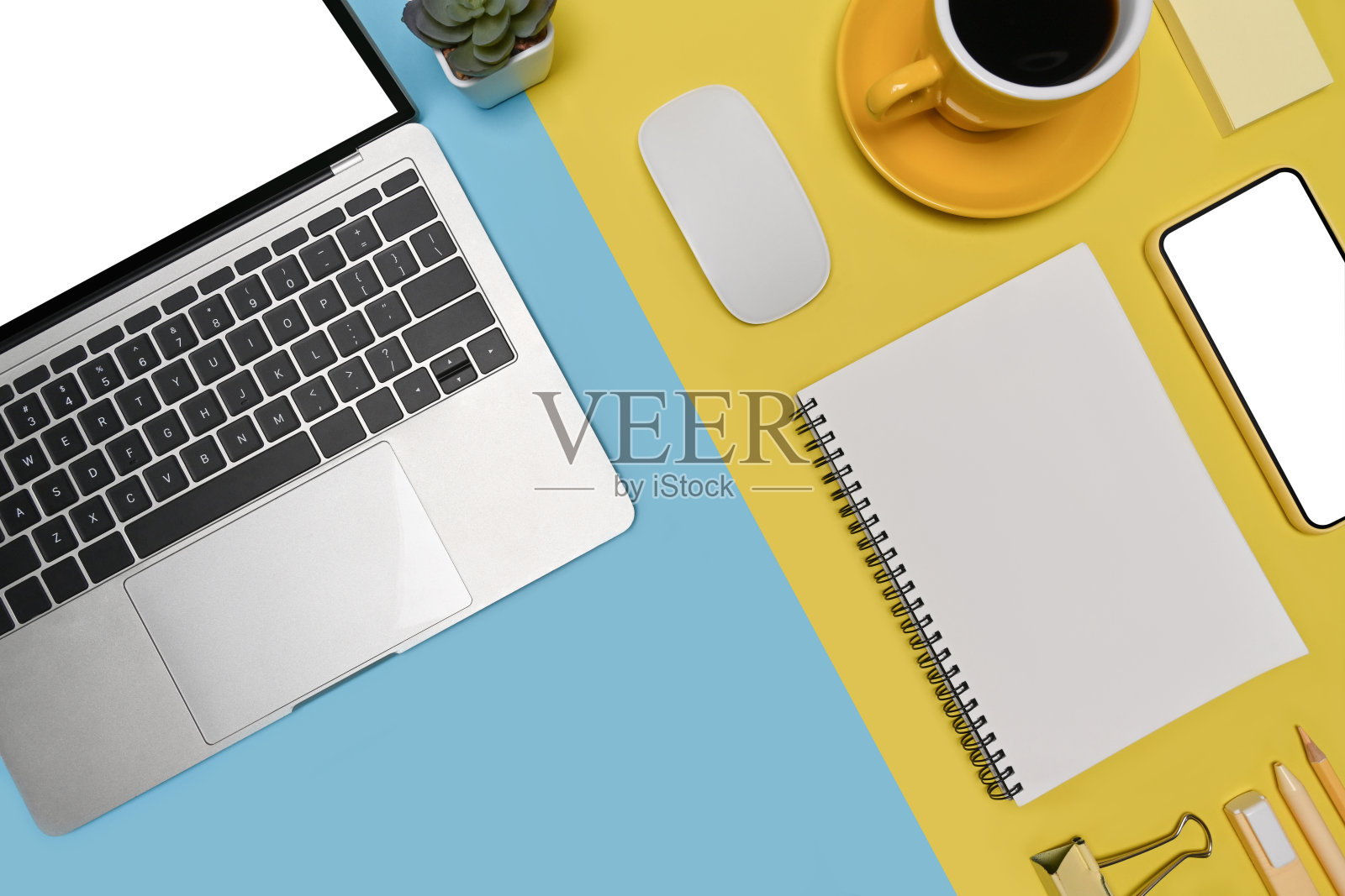 智能手机，笔记本电脑和咖啡杯在两种色调的蓝色和黄色背景。照片摄影图片