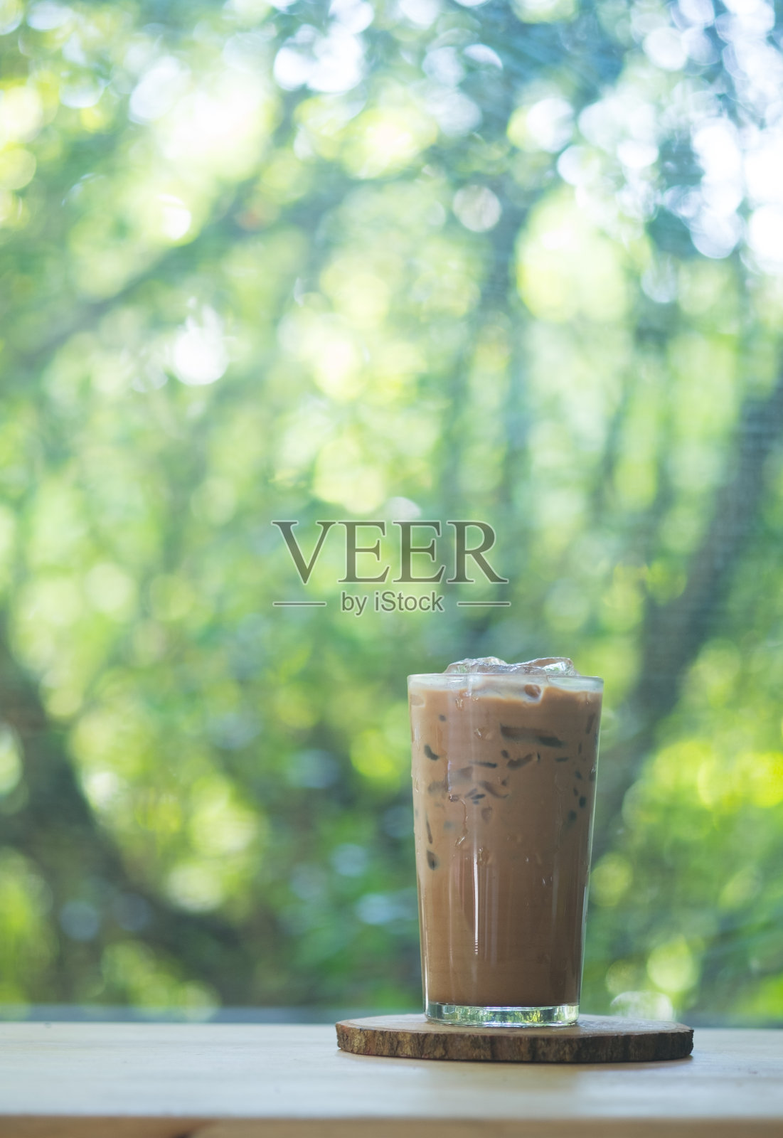 木桌上放着一杯冰摩卡咖啡，背景是大自然照片摄影图片