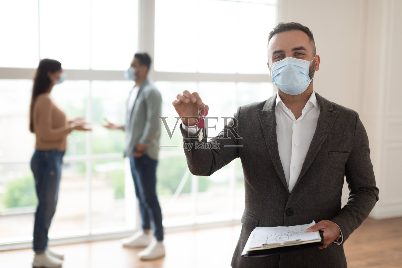 微笑的房地产经纪人戴着口罩展示钥匙照片摄影图片