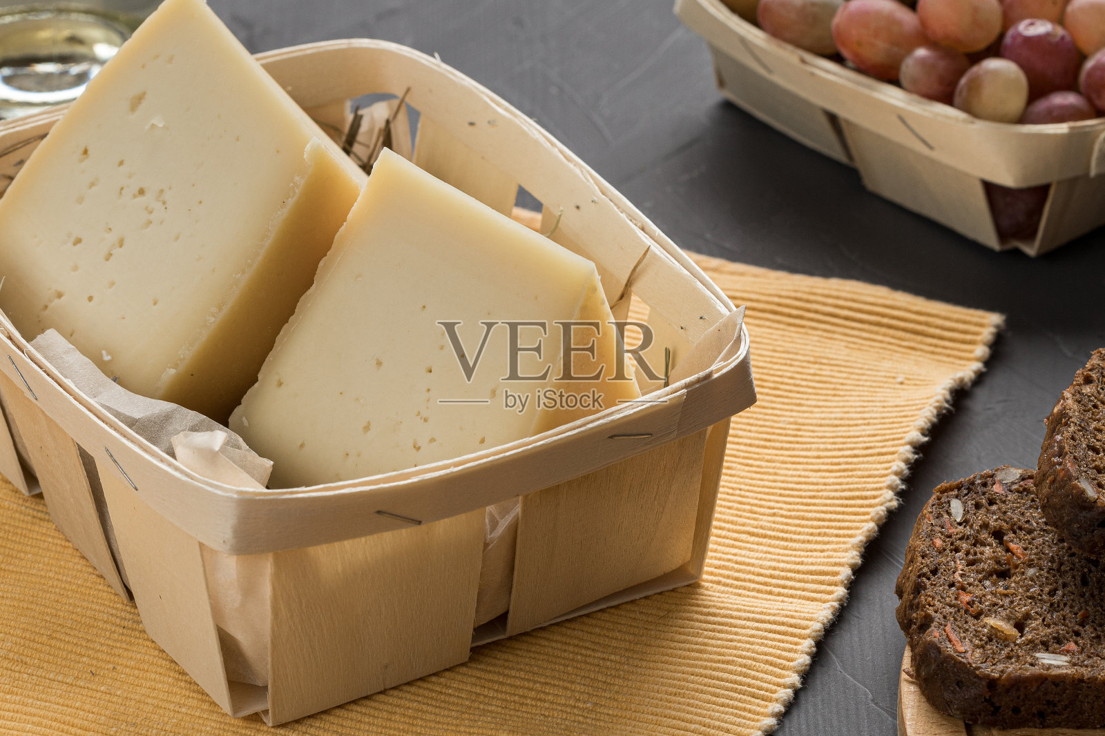 木制的奶酪篮子，深色的背景和面包照片摄影图片