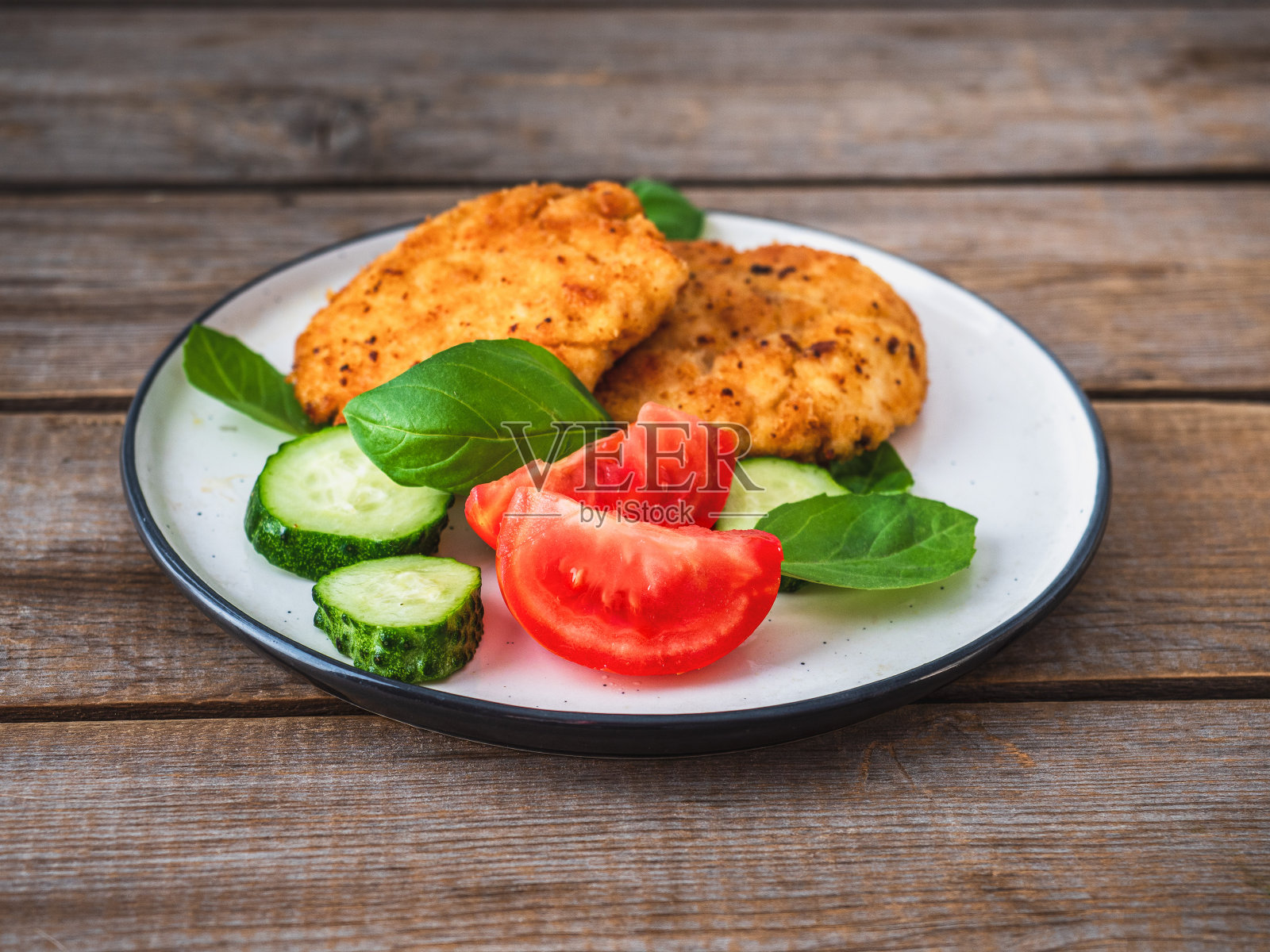 鸡排配蔬菜，黄瓜，西红柿和罗勒放在一个轻盘子里照片摄影图片