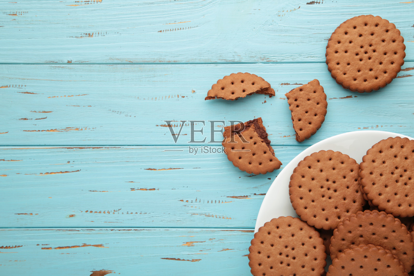 白色的盘子上放着巧克力饼干，蓝色的木头背景。前视图。照片摄影图片