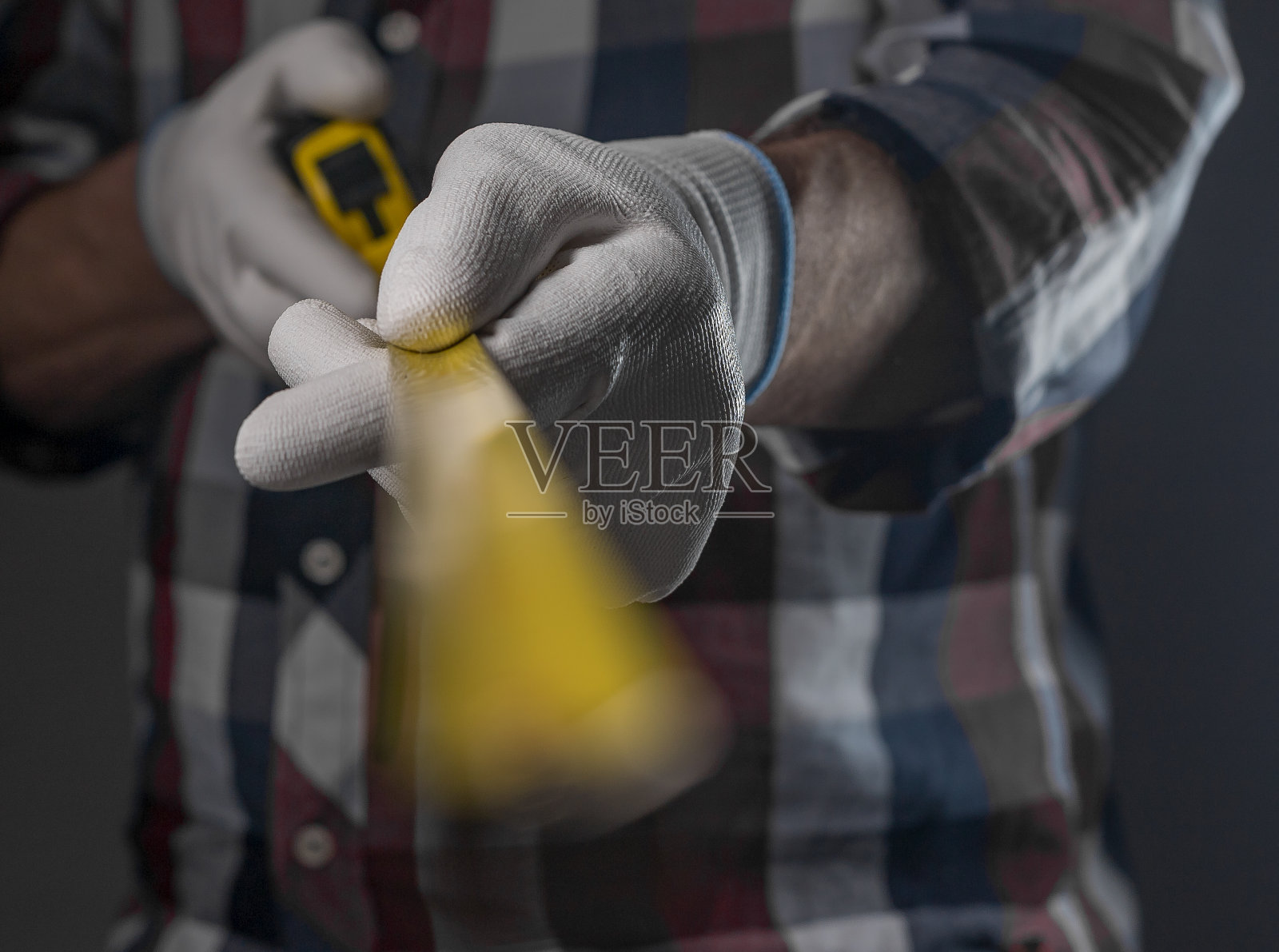男性双手戴白色施工手套，手持黄色伸缩卷尺工具走向镜头，特写照片摄影图片