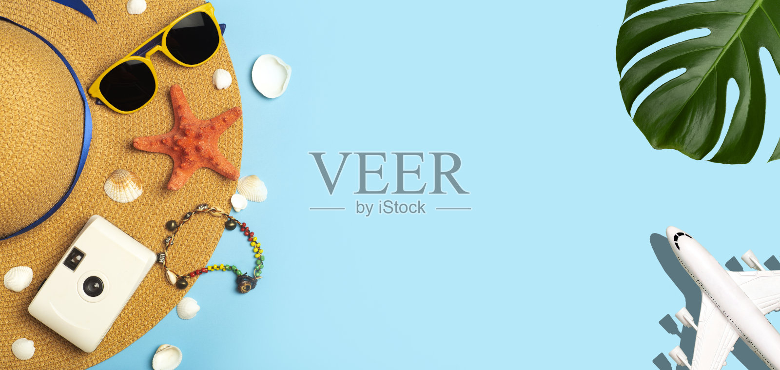 夏天旅游的背景。太阳镜，帽子，棕榈热带树叶，贝壳，飞机和海滩配件在一个彩色的蓝色背景。旅游度假、休闲度假、避暑理念。照片摄影图片