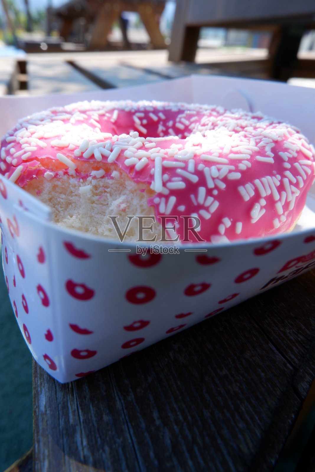 微距拍摄粉红色的咬着甜甜圈照片摄影图片