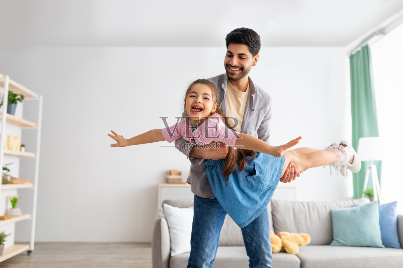 快乐的父亲在家和孩子玩耍，像飞机一样举着女儿照片摄影图片