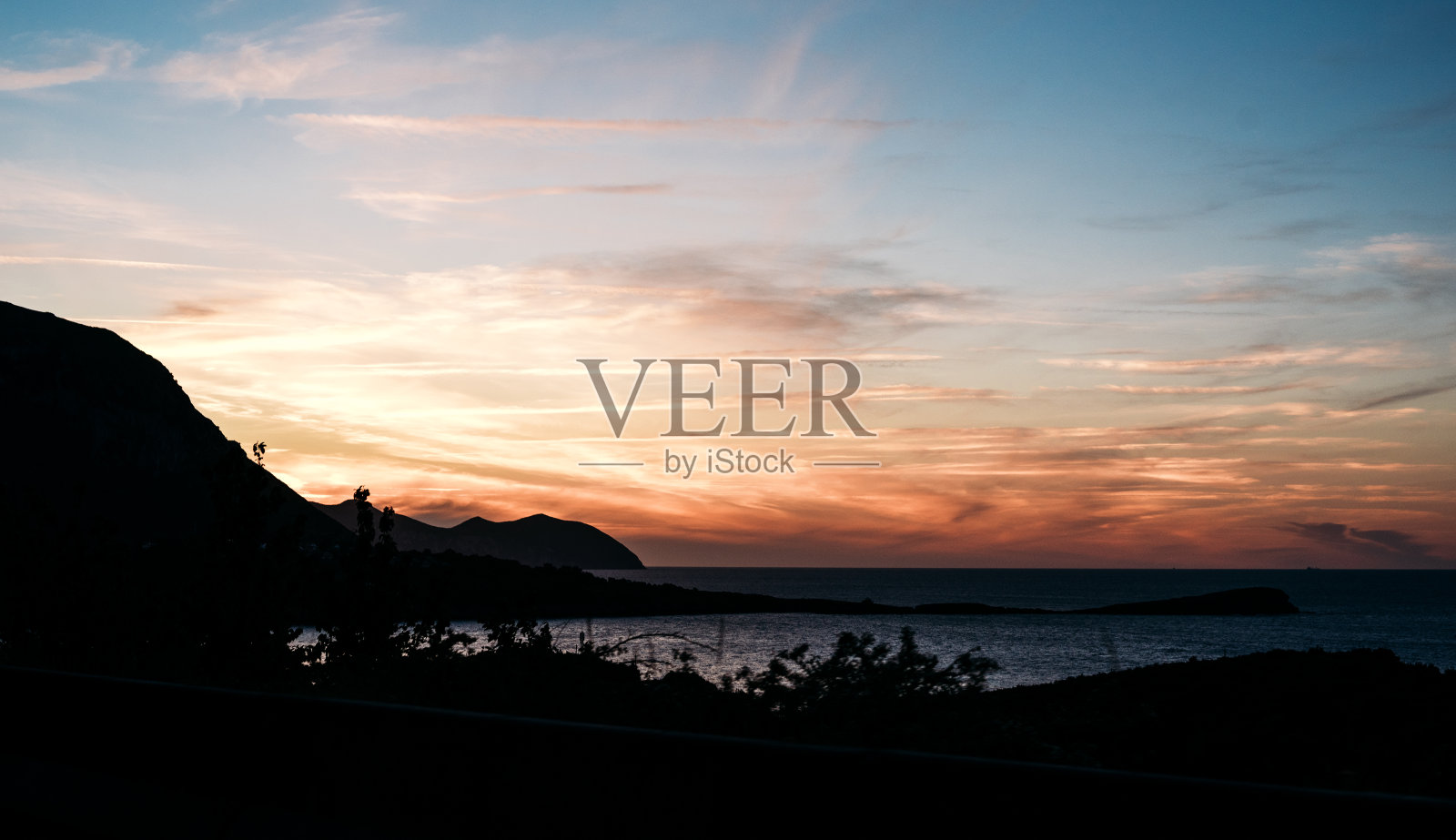 风景优美的日落天空在起伏的大海附近的丘陵海岸照片摄影图片