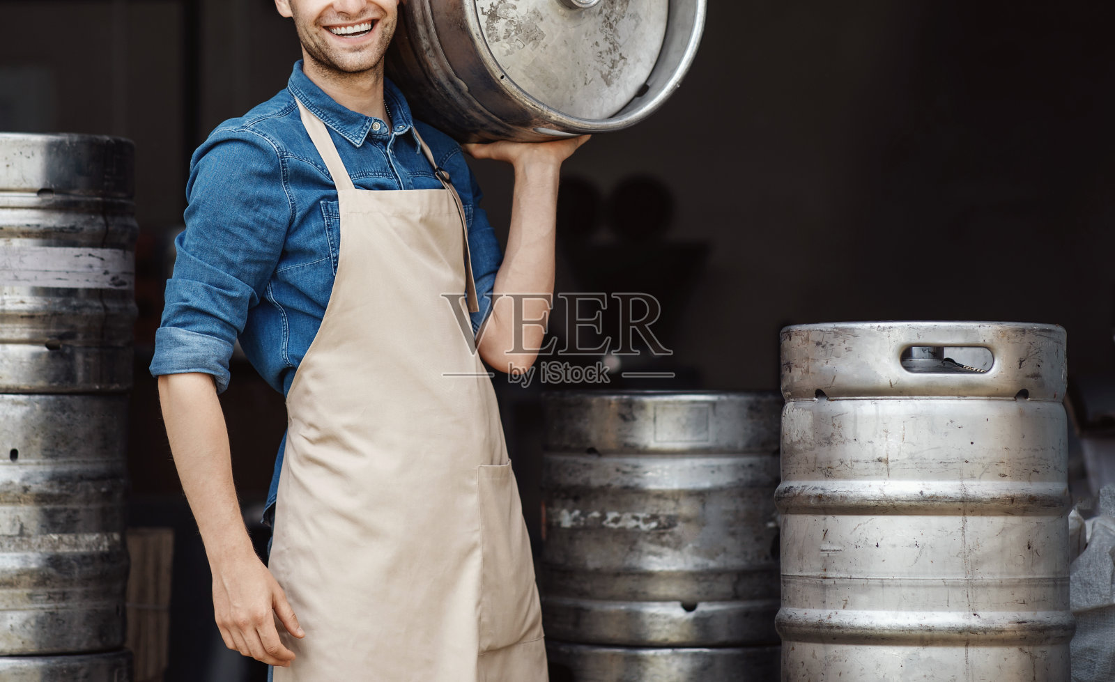 强壮的家伙在酿酒厂工艺酒精生产工作。新冠肺炎疫情下的初创企业和小企业照片摄影图片