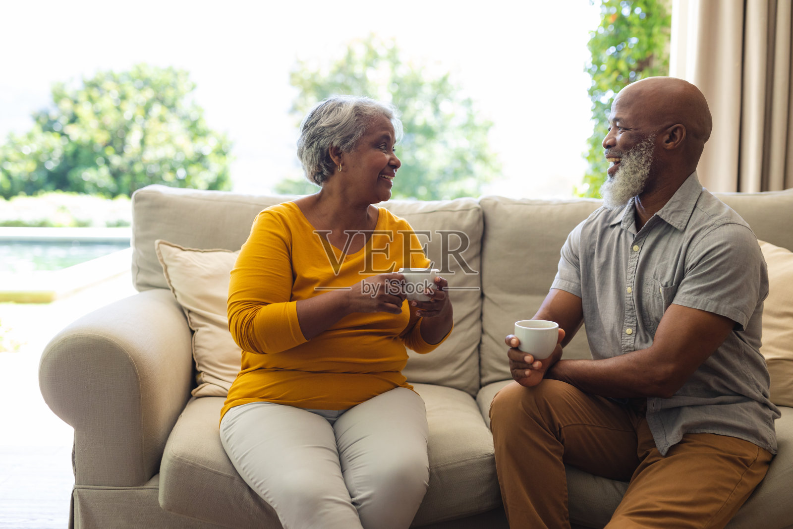 一对非洲裔美国夫妇坐在客厅的沙发上喝咖啡照片摄影图片