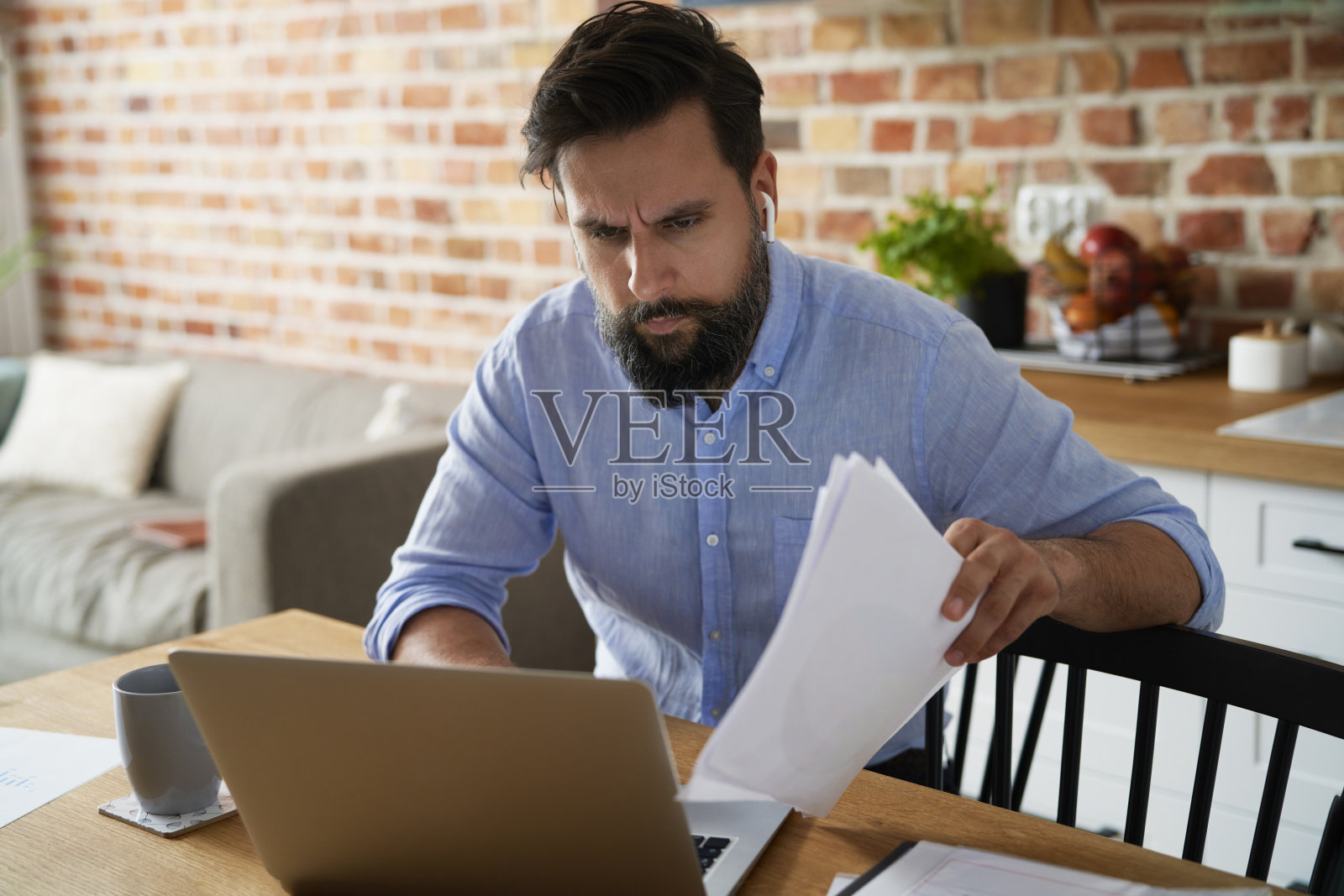 拿着文件在家用笔记本电脑工作的男人照片摄影图片