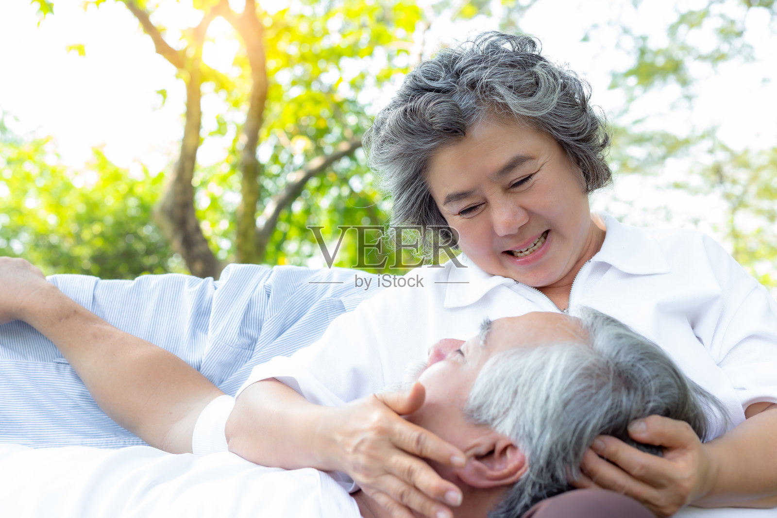 一对老夫妇在公园的长椅上休息，快乐的老夫妇在一个阳光明媚的日子里在公园里微笑照片摄影图片