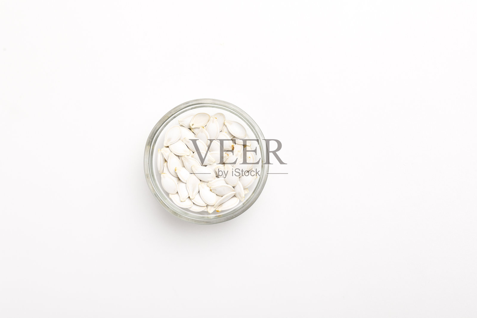 碗里的南瓜籽堆在白色的背景上照片摄影图片