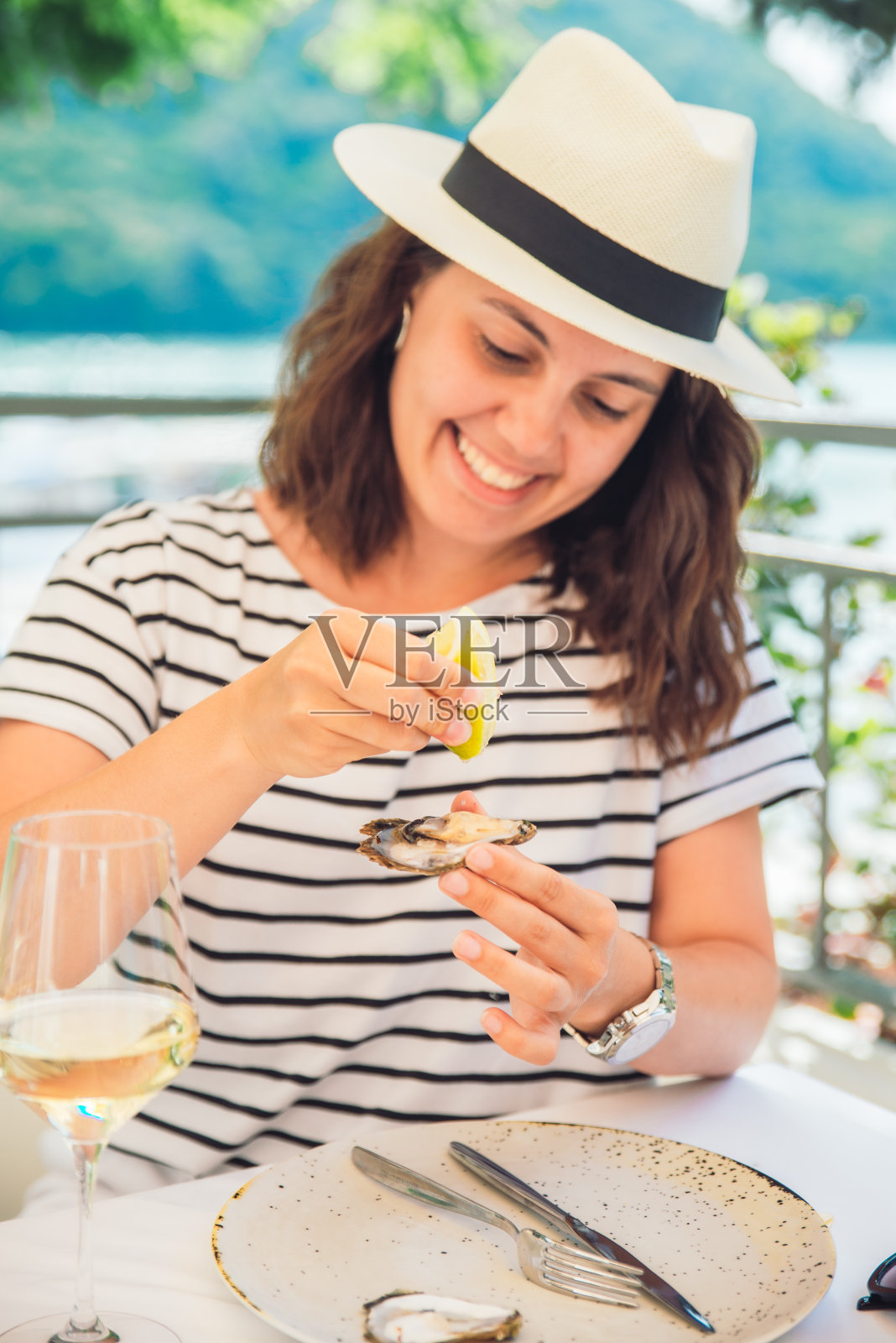 在阳光明媚的夏天，妇女在户外餐厅吃牡蛎照片摄影图片