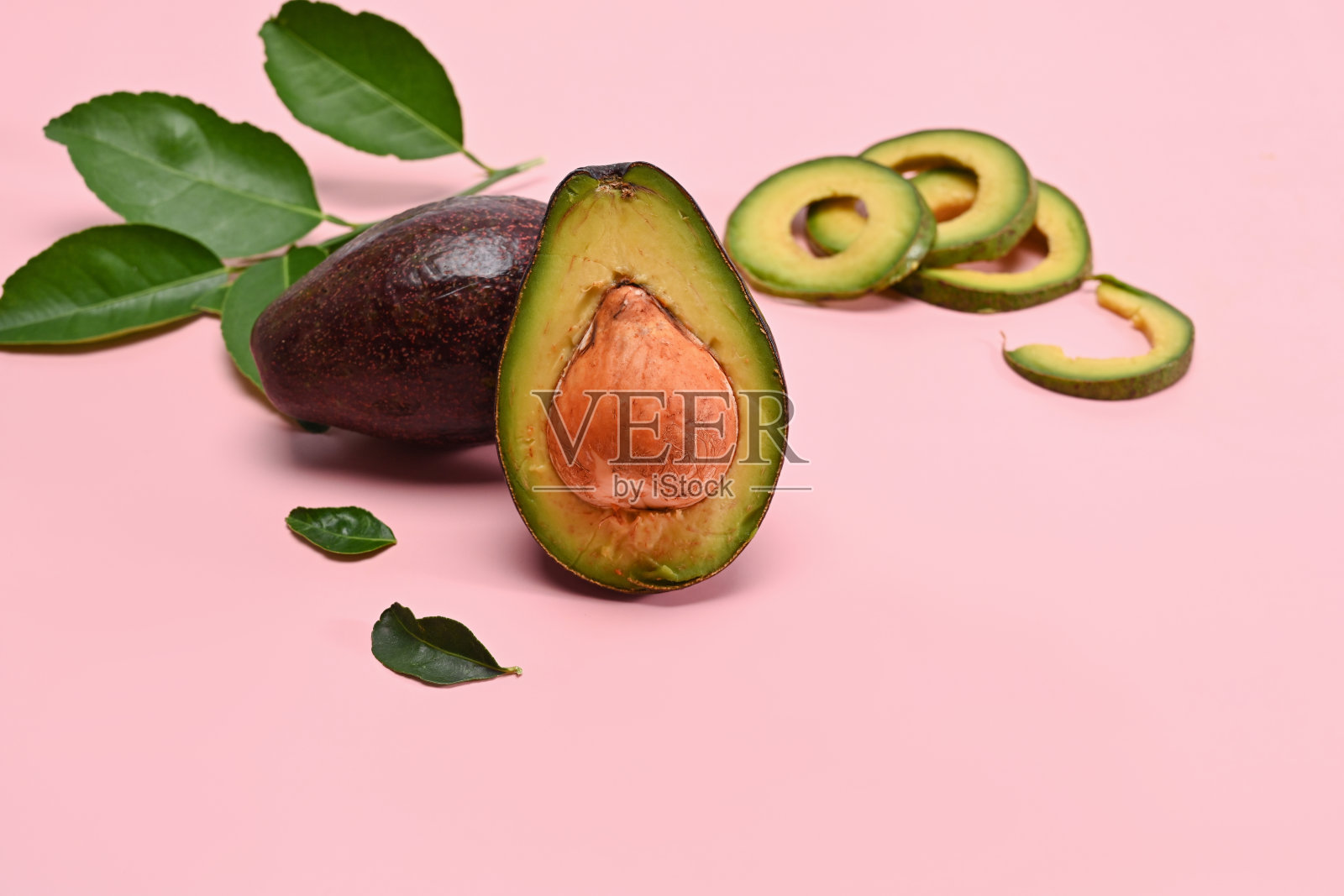 粉色背景下的整个和半鳄梨。水果健康食品理念。照片摄影图片
