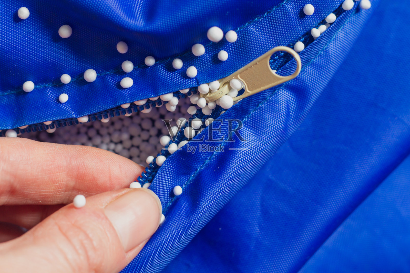 电动轻质泡沫填充物粘在拉链，手，蓝色织物上照片摄影图片