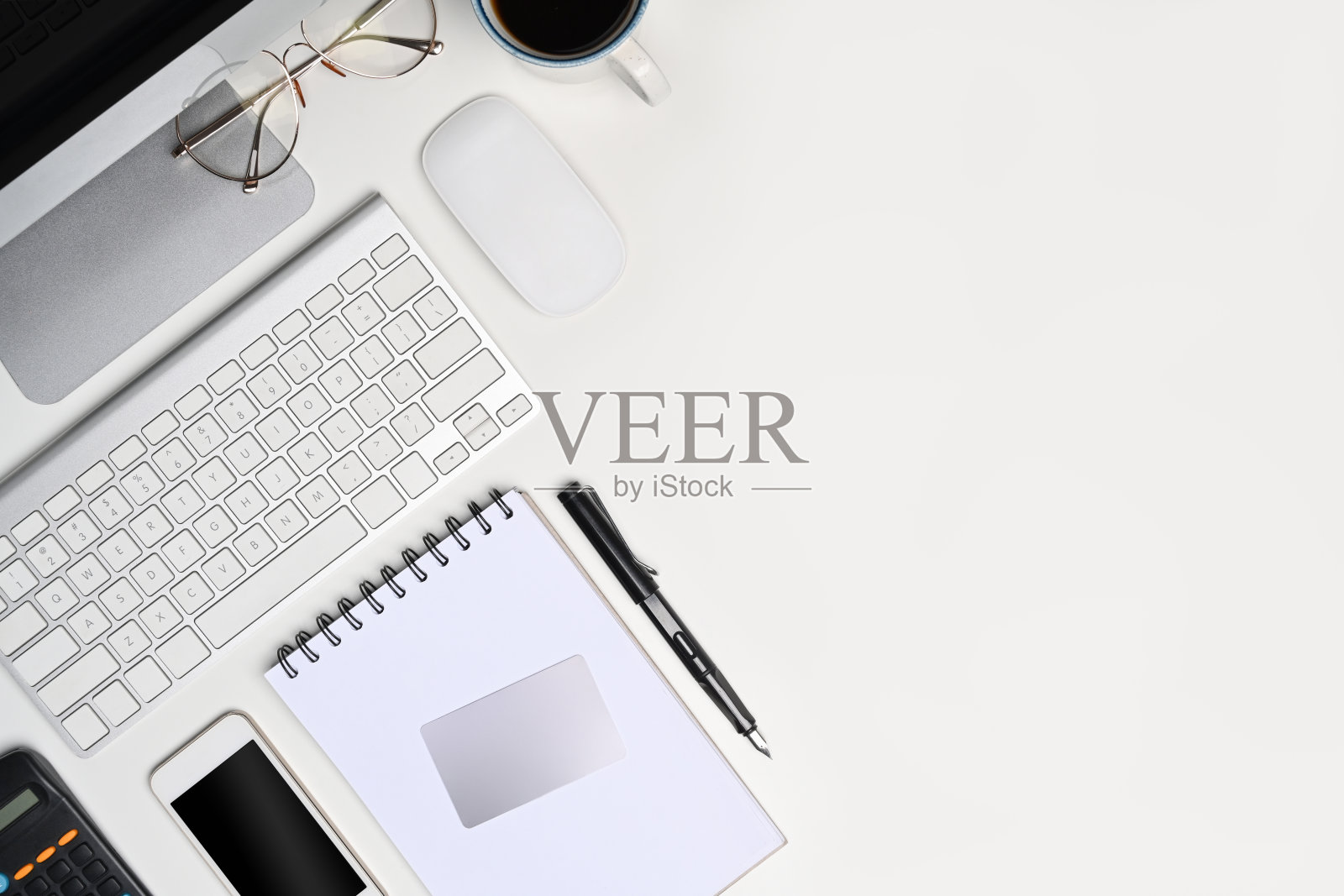 配有智能手机、笔记本、计算器和眼镜的白色办公桌。照片摄影图片