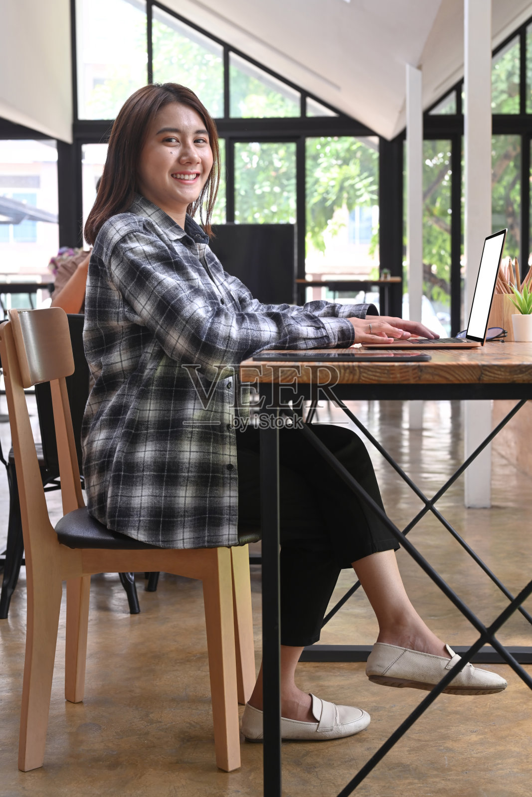 全身像快乐的女商人坐在办公室和微笑的相机。照片摄影图片