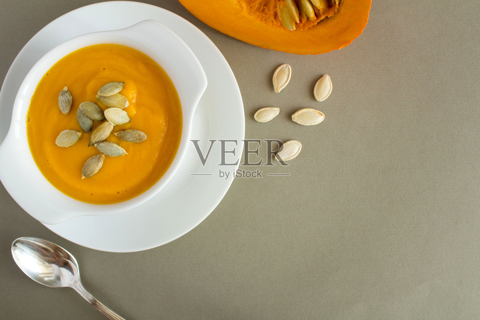 灰色背景下白色盘子里的南瓜汤。前视图。照片摄影图片